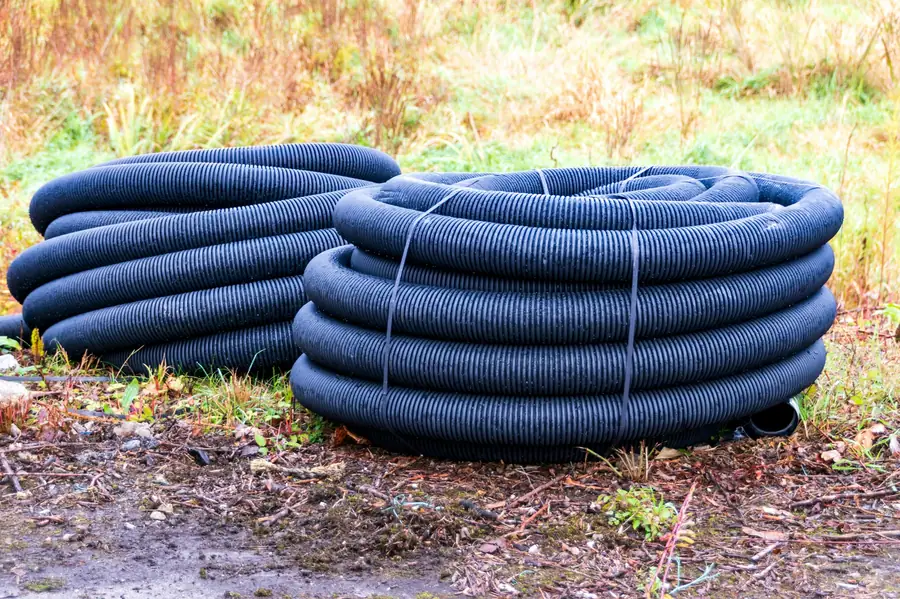 Coiled black drainage pipes on a construction site