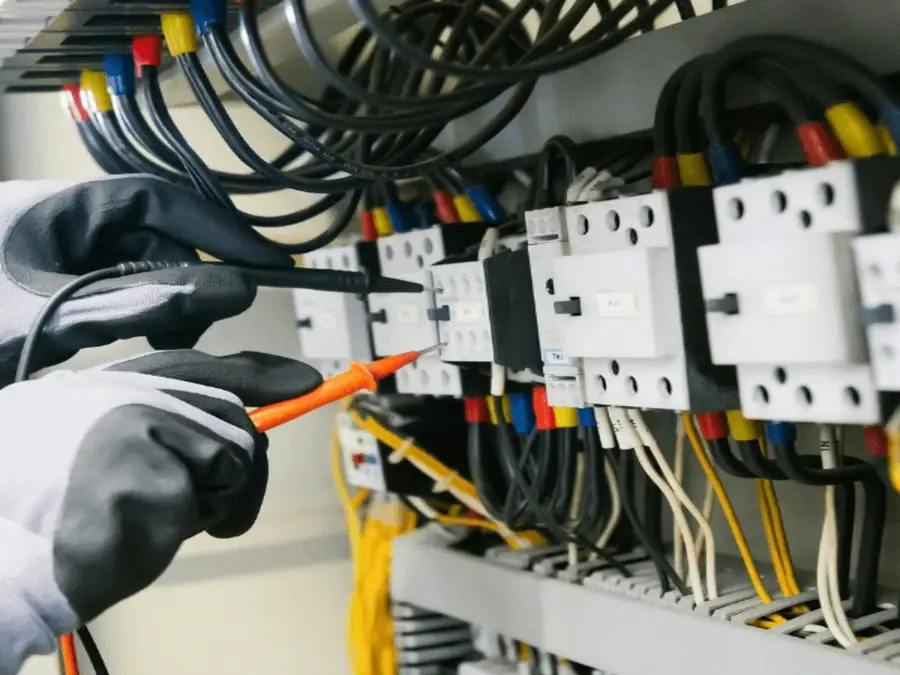 Electrician testing an electrical switchboard with a multimeter