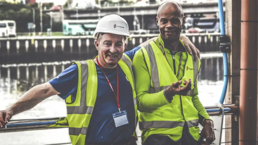 Two site supervisors in green hi-vis vests on a work site