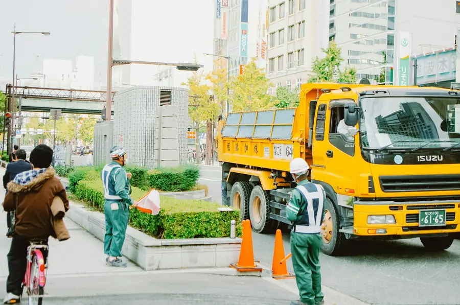 Workers directing traffic near a truck at a work site
