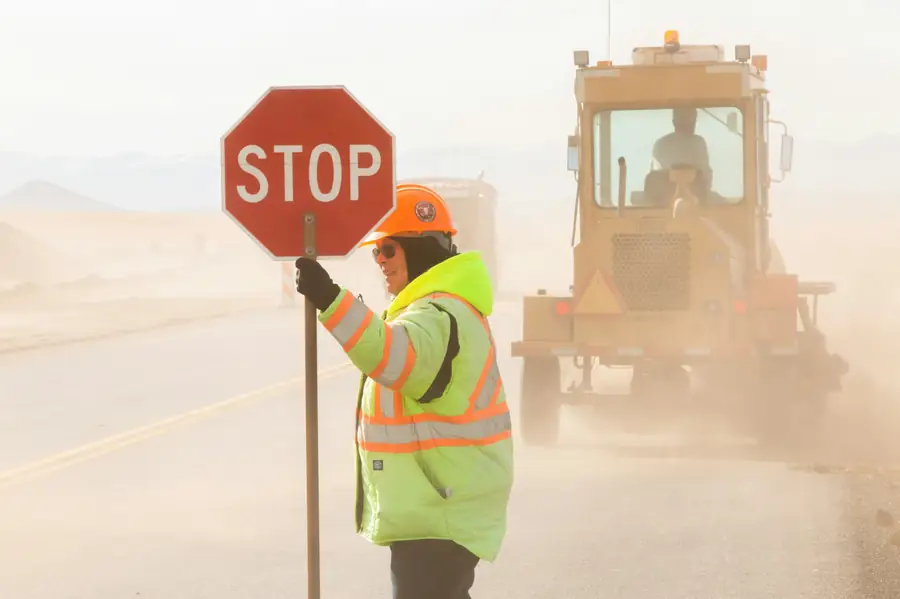 Traffic controller in hi-vis holding a stop sign at roadworks